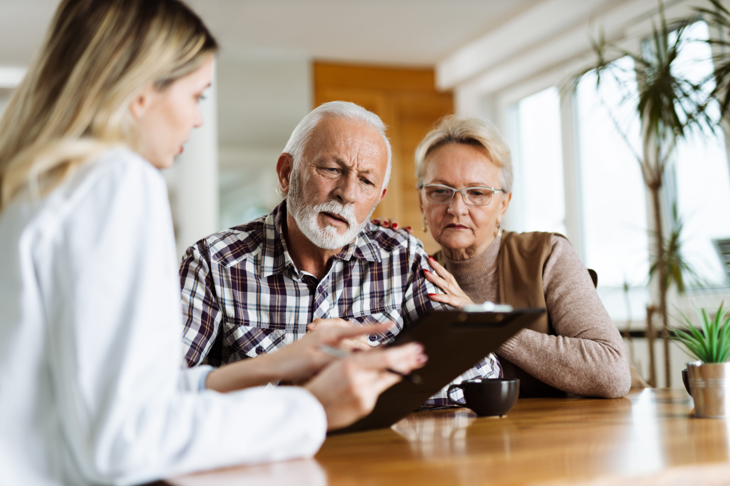 Senior couple looking at health care plan with their home caregi